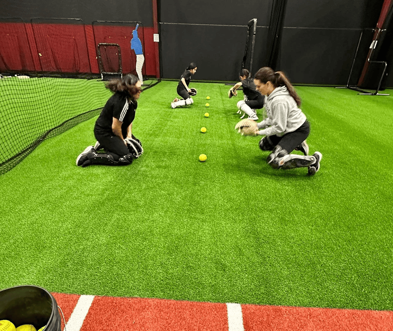 Softball players practicing catching on turf field.